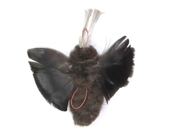 May include: A small, black, fluffy, bird-shaped ornament with wings made of feathers. The ornament has a copper wire loop at the top for hanging.