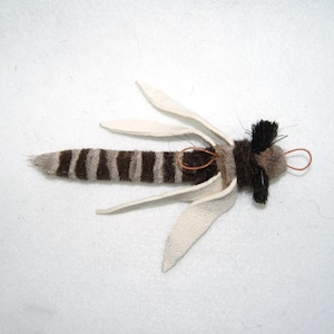 May include: A handmade fly fishing lure with brown and white striped fur, white leather wings, and a brown and black fur head.