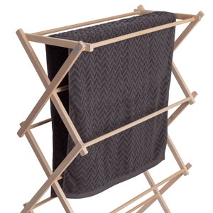 Könnte beinhalten: Ein Wäscheständer aus Holz mit einem dunkelgrauen Handtuch, das darauf hängt. Der Wäscheständer hat drei Ebenen und ist aus Naturholz gefertigt.