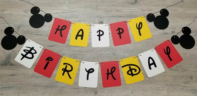 Puede incluir: Una pancarta roja, amarilla y blanca con las palabras "Happy Birthday" en letras negras. La pancarta est&aacute; decorada con cabezas de Mickey Mouse negras.