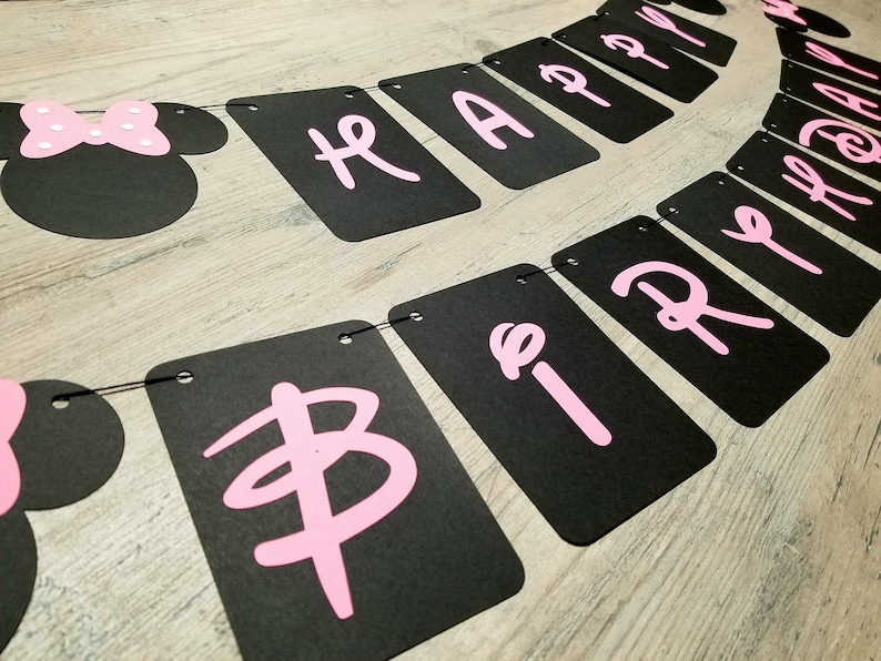 May include: Black and pink banner with the words "Happy Birthday" in pink letters. The banner is strung together with black string and has a black and pink Minnie Mouse head at the end.