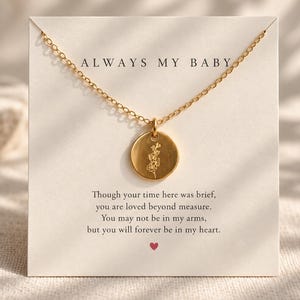 May include: A gold-toned necklace with a circular pendant featuring an engraved floral design. The necklace is displayed on a white card printed with the text ALWAYS MY BABY and a poem about loss, ending with a small red heart symbol at the bottom.