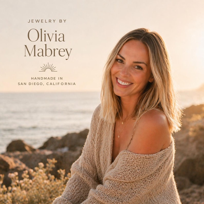 May include: A person with shoulder-length blonde hair wearing a beige knit sweater. Text on the image reads: JEWELRY BY Olivia Mabrey, a sun icon, and HANDMADE IN SAN DIEGO, CALIFORNIA. The setting is a coastal area during a sunset.