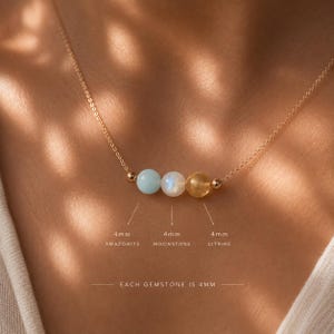 May include: A delicate gold chain necklace featuring three 4mm round gemstones: a light blue amazonite, a white moonstone, and a yellow citrine. The text labels indicate each gemstone is 4mm in size, with the total gemstone size being 4mm.
