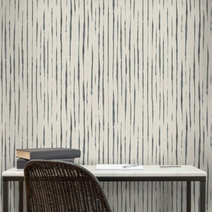 May include: A white desk with a black metal frame and a black wicker chair. The wall behind the desk has a white and gray striped wallpaper pattern.