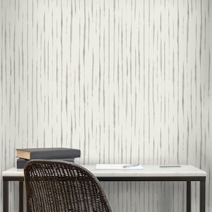 May include: A white desk with a black metal frame and a black wicker chair. The desk has a white surface and a black pen and a white notepad on it. The wall behind the desk has a white and gray striped pattern.