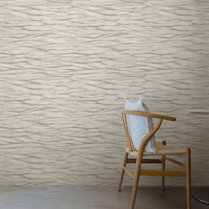 May include: A wooden chair with a white cushion and a woven seat sits in front of a wall with a light gray and white wavy pattern wallpaper.