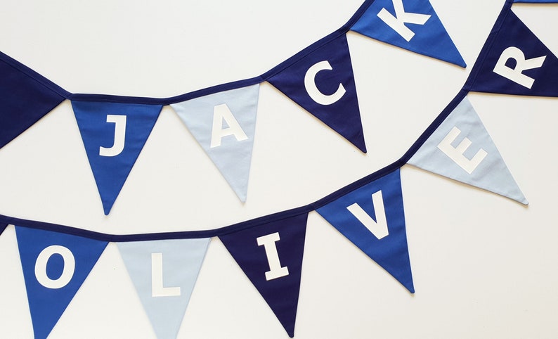 May include: A blue and white pennant banner with the names "JACK" and "OLIVER" spelled out in white capital letters. The pennants are in shades of blue, with a white background.