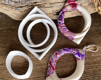May include: Two white plastic earring cutters with a diamond-shaped outer frame and oval inner frame, alongside two finished earrings featuring a marbled pattern of purple, magenta, and white swirls paired with a smooth, pearlescent off-white section.
