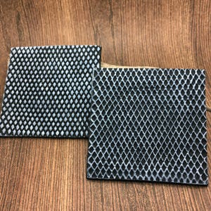 以下が含まれることがあります： 黒と白のパターンが施されたゴム製のマットが2枚。マットはダイヤモンドパターンで、質感があります。