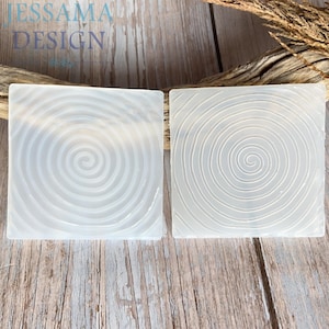 May include: Two square, translucent silicone molds featuring a raised, concentric spiral pattern on the surface. The molds are clear and flexible, designed for casting, with the text JESSAMA DESIGN visible in the upper left corner of the image.