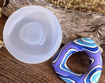 May include: A translucent, circular silicone mold next to a triangular, hollow pendant featuring a marbled pattern of purple, light blue, dark blue, and white swirls. The text JESSAMA DESIGN is visible in the upper left corner.