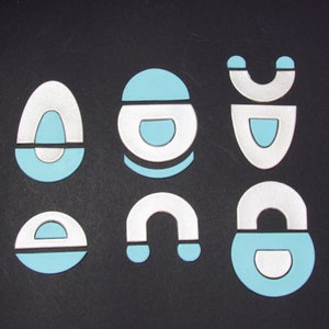 May include: Six different shapes made of white and light blue paper. The shapes are a circle, a teardrop, a crescent moon, a rectangle, a half circle, and a teardrop with a half circle on top.