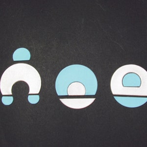 May include: Three abstract geometric shapes in blue and white. The shapes are a horseshoe, a circle with a smaller circle inside, and a circle with a smaller circle cut out.