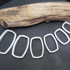 May include: Set of seven white plastic cookie cutters shaped like rounded rectangles, arranged in a row from largest to smallest.