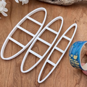 May include: Three white plastic bangle making moulds with four sections each. The moulds are arranged in a fan shape. A blue and yellow patterned bangle is shown in the lower right corner.