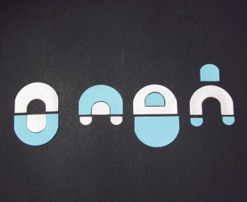 May include: Four blue and white ceramic pieces in the shape of a horseshoe, a letter A, a letter D, and a horseshoe. The pieces are arranged in a row on a black background.