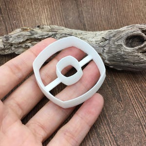 以下が含まれることがあります： 中央に穴の開いたドーナツの形をした白いプラスチック製のクッキーカッター