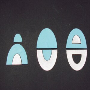 May include: Three blue and white geometric shapes on a black background. The shapes are all different sizes and have a variety of curves and lines.