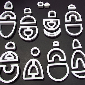 May include: A set of 10 white plastic geometric shapes, including circles, semi-circles, and arches, arranged in a pattern on a black background.