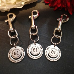May include: Three silver keychains with round metal tags. Each tag has a different inscription: "Church of Angels 81", "Bad Bitch 81", and "Support 81". All tags have the text "Suffolk County, NY" and "Follow Me to the Clubhouse".
