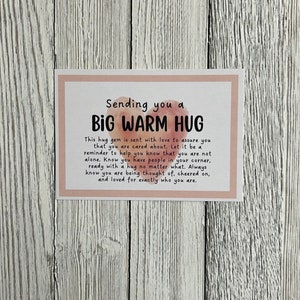 Puede incluir: Una tarjeta rosa y blanca con el texto "Sending you a BIG WARM HUG" y un mensaje para enviar un abrazo a alguien que lo necesita.