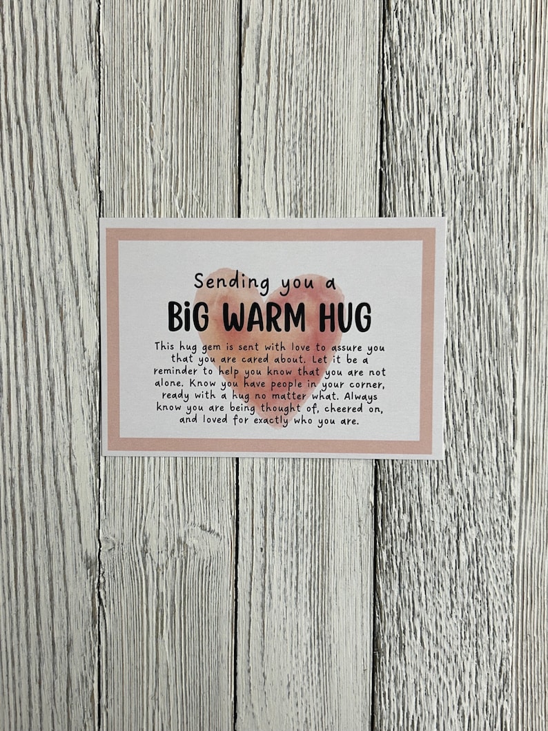 Puede incluir: Una tarjeta rosa y blanca con el texto "Sending you a BIG WARM HUG" y un mensaje para enviar un abrazo a alguien que lo necesita.