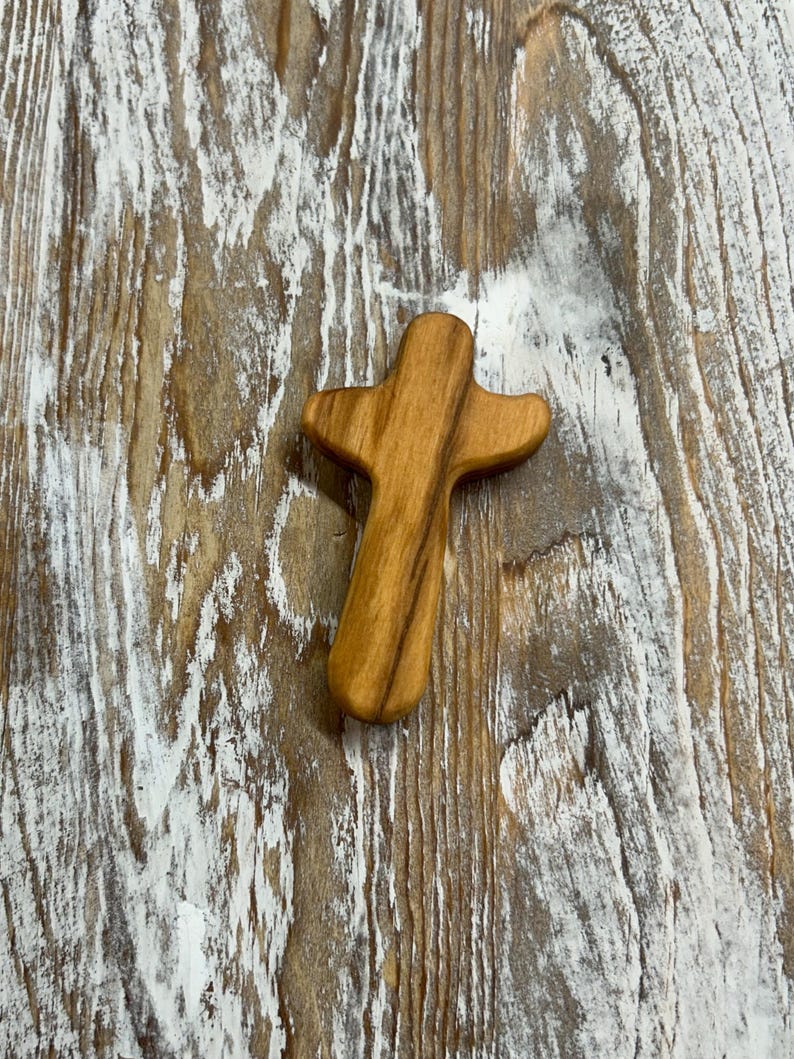 May include: A small, wooden cross with a natural wood finish. The cross is made of a light brown wood and has a simple, rustic design.