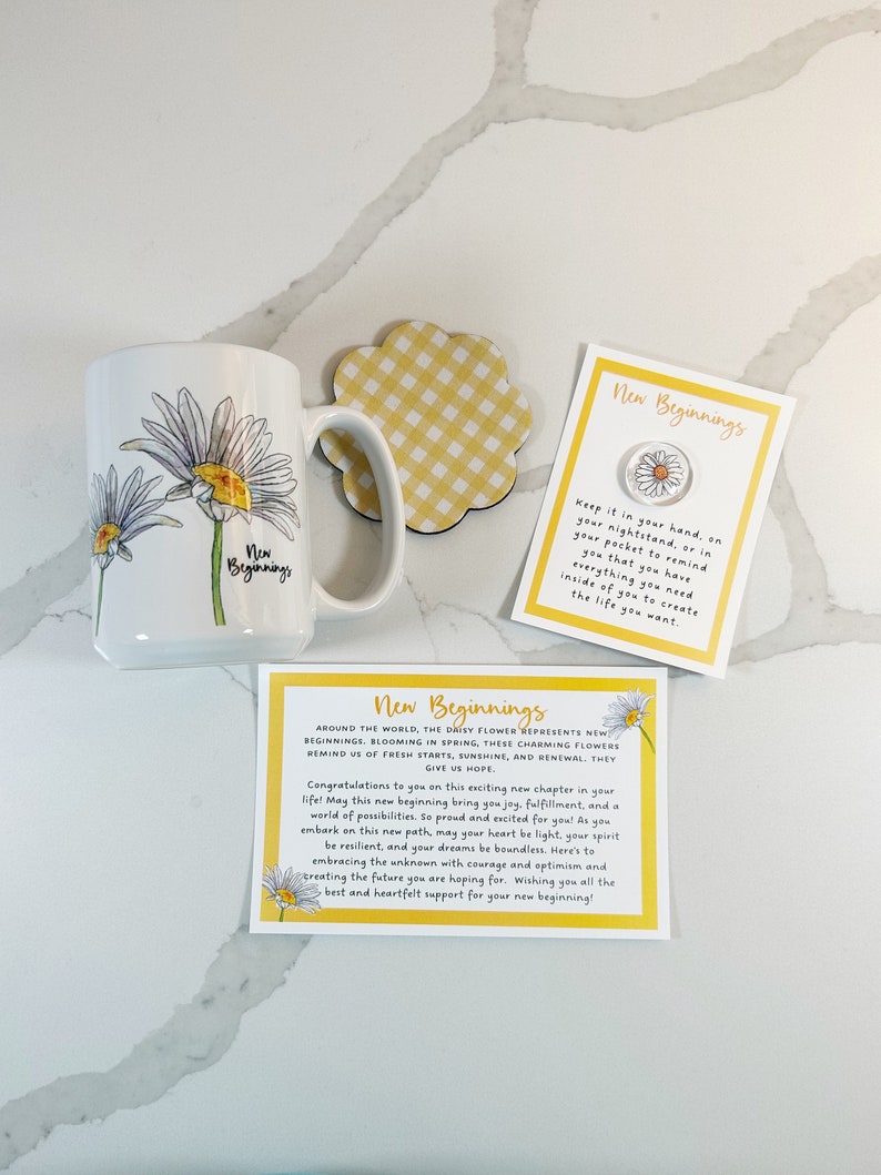 Pu&ograve; includere: Una tazza bianca con un manico giallo presenta un design con un fiore di margherita. La tazza &egrave; accompagnata da un sottobicchiere a quadri gialli e da un biglietto con il testo "Nuovi Inizi" e una grafica di margherita. Il biglietto recita "Tienilo in mano, sul tuo comodino o in tasca per ricordarti che hai tutto ci&ograve; di cui hai bisogno dentro di te per creare la vita che vuoi."