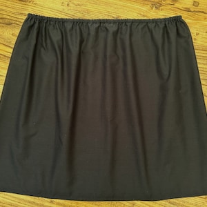 May include: A black cotton slip skirt with a gathered elastic waistband.