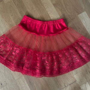 May include: A red tulle petticoat with lace trim. The petticoat has a satin waistband and multiple layers of tulle.
