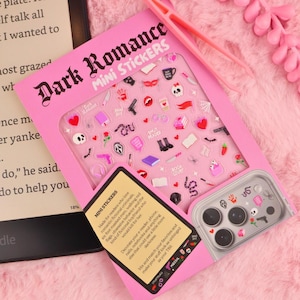 Könnte beinhalten: Ein rosa Bogen mit Dark Romance Mini-Aufklebern, die verschiedene kleine Symbole wie Totenköpfe, Messer, Herzen und Bücher zeigen. Die Verpackung enthält eine rosa Pinzette und einen Bereich, der die Anwendung auf einer Smartphone-Kamera zeigt.