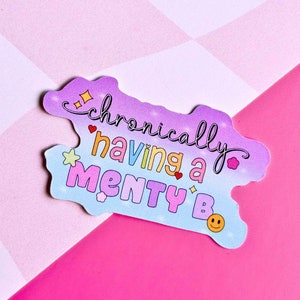 Op de afbeelding: Een sticker met een regenboogkleurige achtergrond en de tekst "chronically having a menty b" in kleurrijke letters. De sticker heeft een glinsterend ontwerp en een smiley.