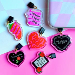 May include: Six colorful acrylic charms with different book-themed designs. The charms feature phrases like "This kindle is full of smut" and "Smut Book Club".