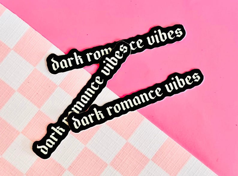 May include: Three black stickers with white text that reads "dark romance vibes" on a pink and white checkered background.
