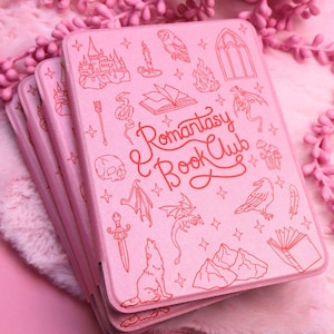 Op de afbeelding: Roze notitieboekjes met rode fantasie-illustraties, op elkaar gestapeld. De notitieboekjes tonen een kasteel, een uil, een draak en andere fantasie-motieven. De tekst "Romantasy & Book Club" staat in rode letters.