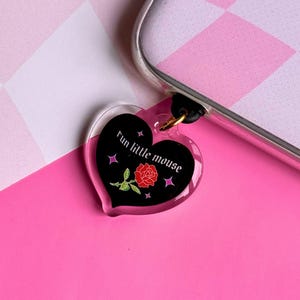 May include: A black heart-shaped phone charm with a red rose and the text "run little mouse" in white.