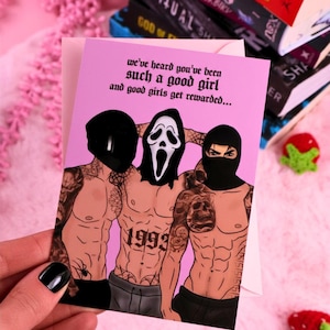 May include: A pink greeting card with the text "we've heard you've been such a good girl and good girls get rewarded..." and an illustration of three shirtless men wearing masks. The card is surrounded by books and pink flowers.