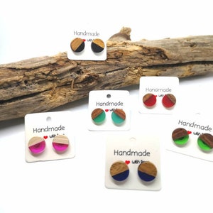 Könnte beinhalten: Fünf Paar handgefertigte Ohrringe mit runden Designs aus Holz und Harz. Die Ohrringe werden auf weißen Karten mit dem Text "Handmade with love" präsentiert. Die Ohrringe haben verschiedene Harzfarben, darunter Schwarz, Rot, Grün, Blau und Pink.