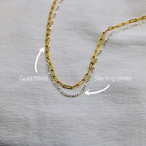 May include: Two gold filled and sterling silver chains, one on top of the other. The gold filled chain is on top and the sterling silver chain is on the bottom. The chains are both in a box link style.