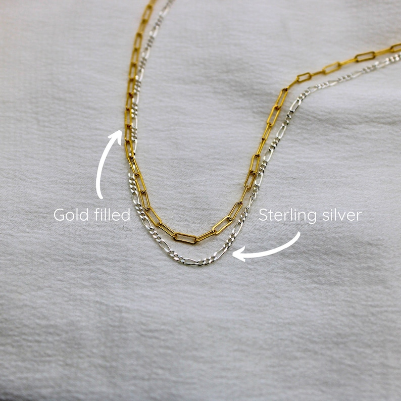 May include: Two gold filled and sterling silver chains, one on top of the other. The gold filled chain is on top and the sterling silver chain is on the bottom. The chains are both in a box link style.