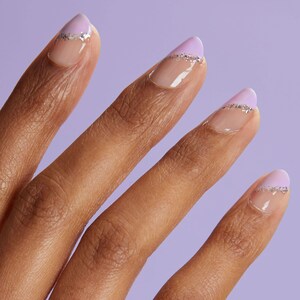 May include: Close-up of a hand with four fingers showing, each with a light purple and silver glitter nail polish design.