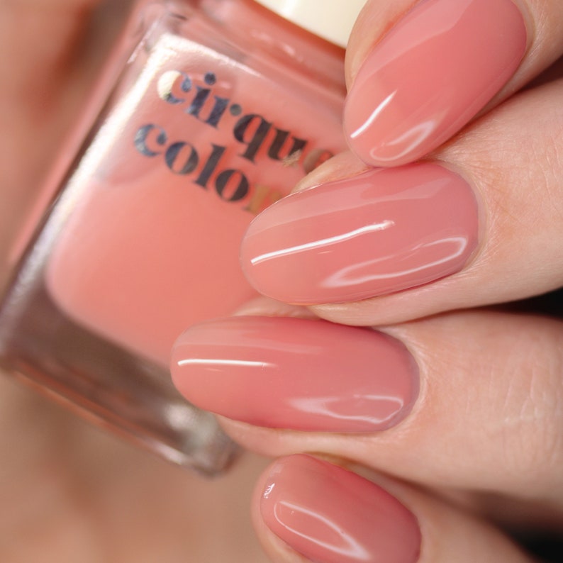 Puede incluir: Primer plano de una mano con esmalte de u&ntilde;as rosa. El esmalte de u&ntilde;as es de la marca Cirque Colors.
