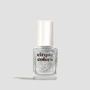 May include: A clear glass bottle of silver glitter nail polish with a white cap. The bottle has the text "cirque colors" printed on the front.