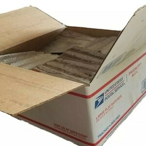 May include: A brown cardboard box with the United States Postal Service logo and the words "PRIORITY MAIL" and "LARGE FLAT RATE BOX". The box is open and filled with brown paper.