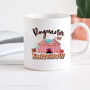 May include: White ceramic mug featuring a red, white and blue circus tent graphic and the text "Ringmaster of the Shit Show".