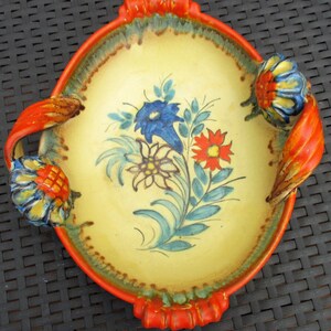 Puede incluir: Un plato de servir de cer&aacute;mica amarillo con asas naranjas y un dise&ntilde;o floral pintado en azul, rojo y verde.