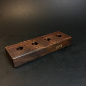 May include: A dark brown wooden stand with five holes for holding items. The stand is engraved with the word "FUTO".