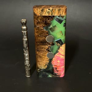 May include: A wooden box with a colorful resin inlay. The box has two magnetic closures and is made of wood with a natural finish. The box is approximately 4 inches tall and 2 inches wide.