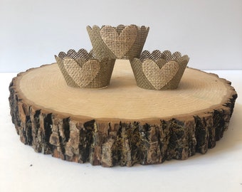 May include: Three brown burlap cupcake liners with a white heart design on a wooden slice.
